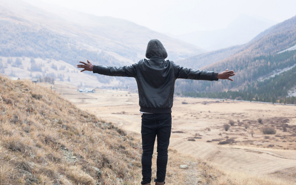 Personne ouvrant les bras face à la montagne